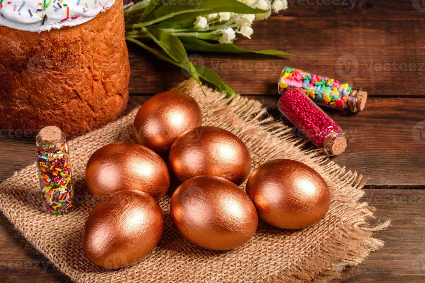 Huevos de pascua de oro y bronce y pastel de pascua sobre un fondo oscuro foto