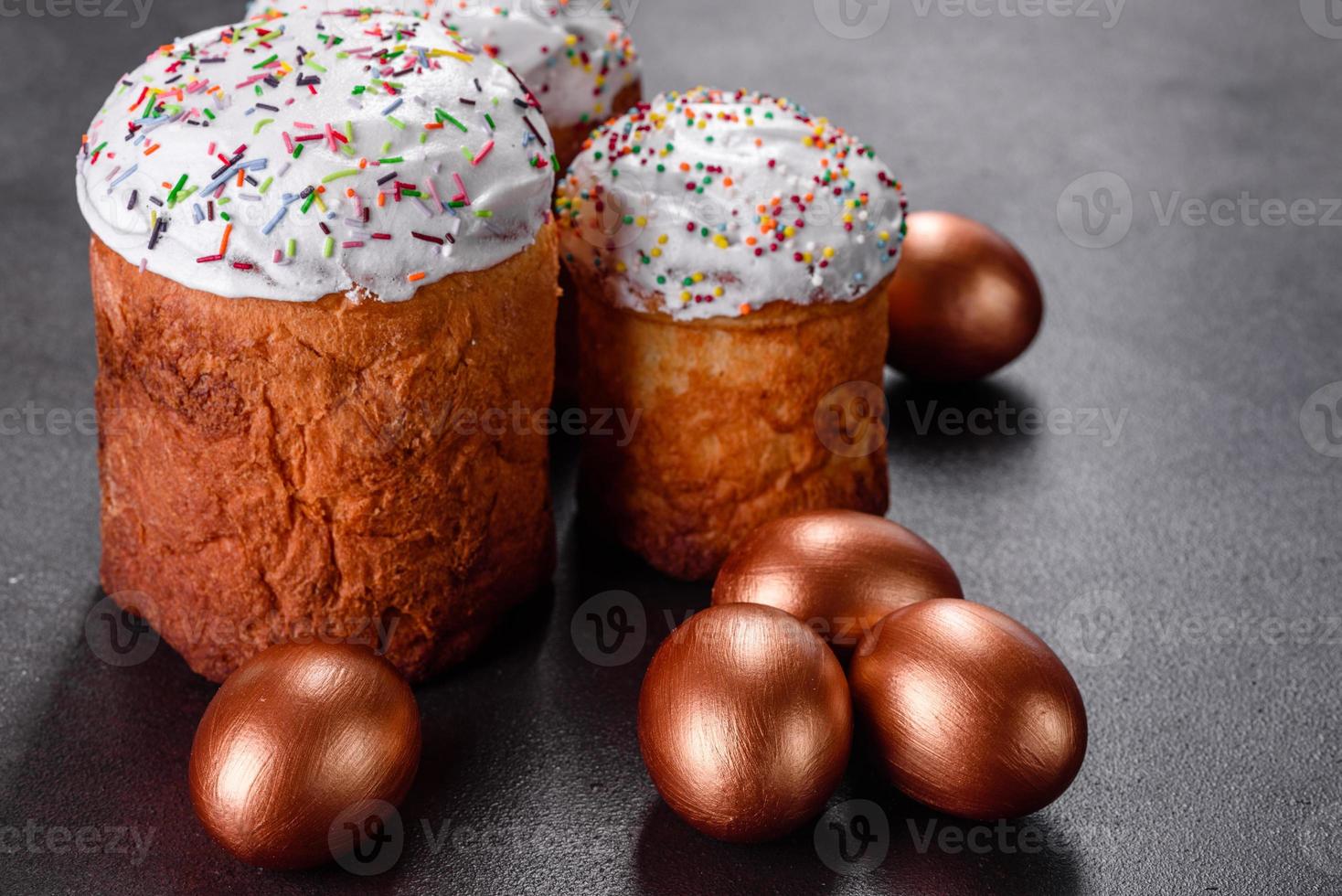 Huevos de pascua de oro y bronce y pastel de pascua sobre un fondo oscuro foto