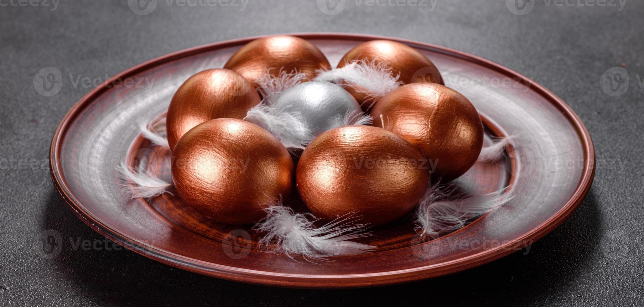 Huevos de pascua de oro y bronce y pastel de pascua sobre un fondo oscuro foto