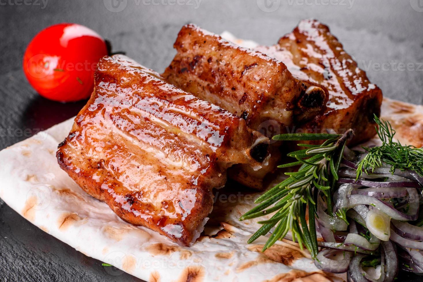 Fried ribs with rosemary, onion, sauce on a concrete background photo