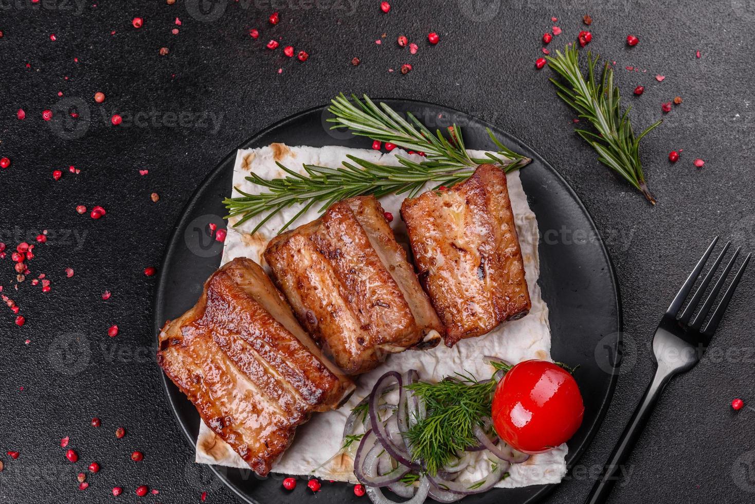 Costillas fritas con romero, cebolla, salsa sobre un fondo de hormigón foto