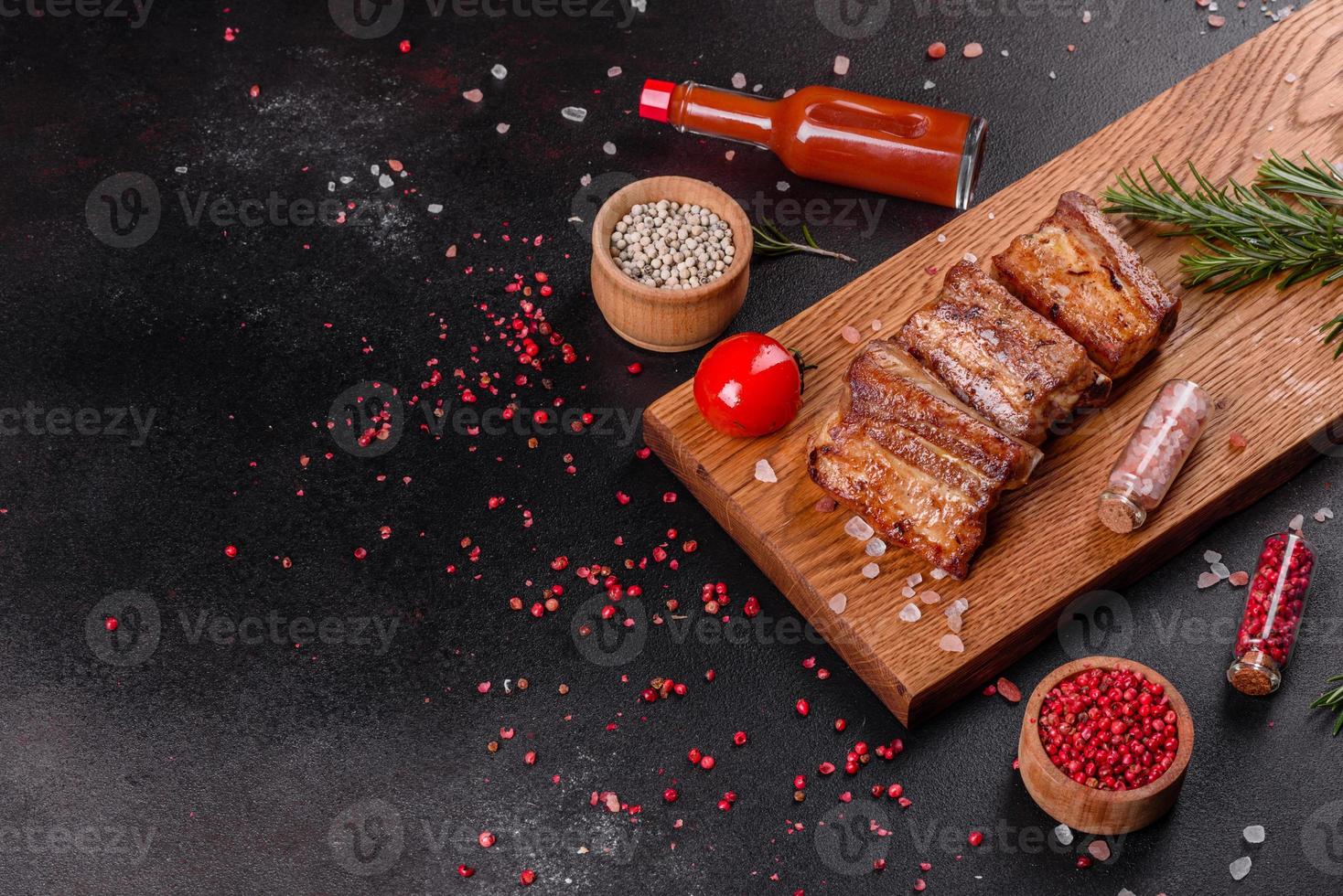 Fried ribs with rosemary, onion, sauce on a concrete background photo