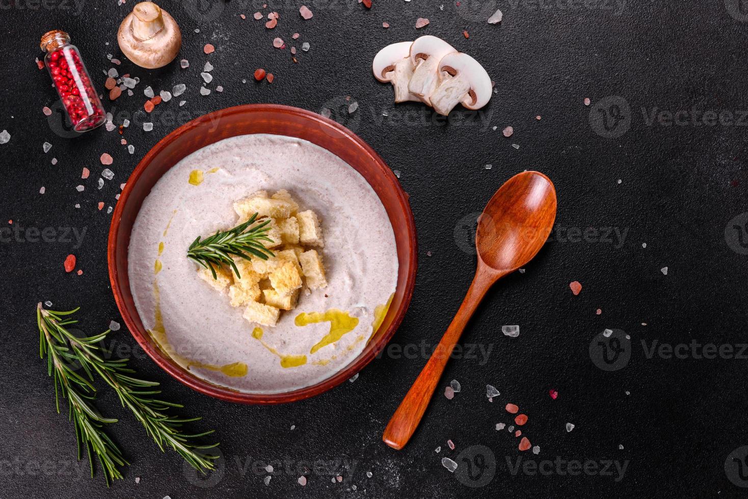 deliciosa sopa de hongos hermosa en un plato marrón con una cuchara de madera foto