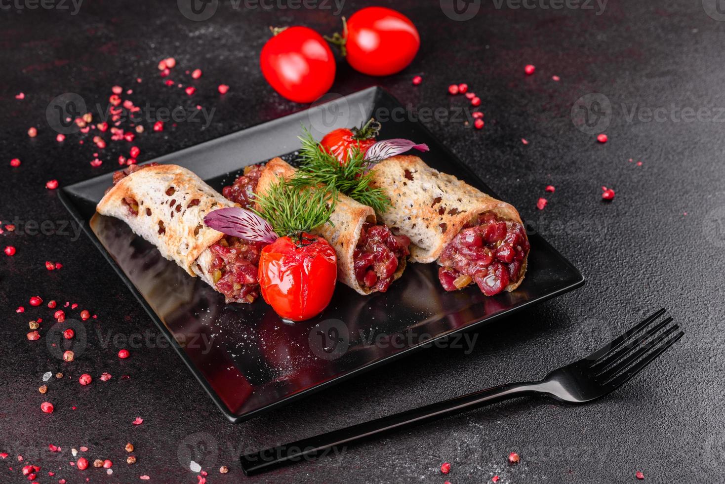 Delicious fresh beef tartar with toasts on a black square plate photo