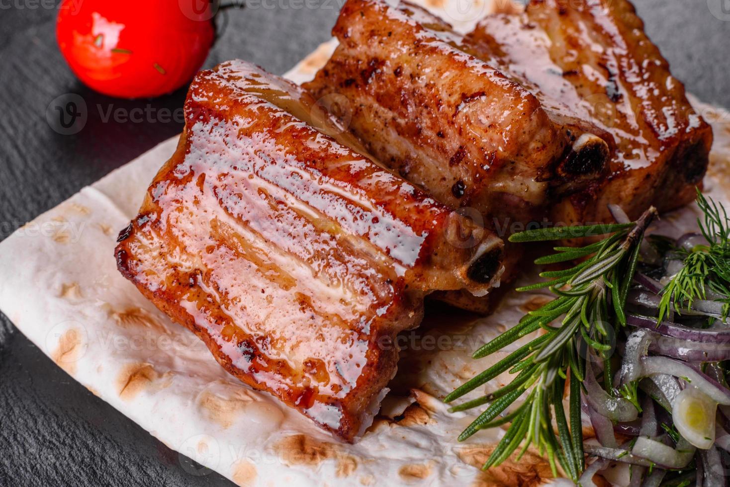 Fried ribs with rosemary, onion, sauce on a concrete background photo