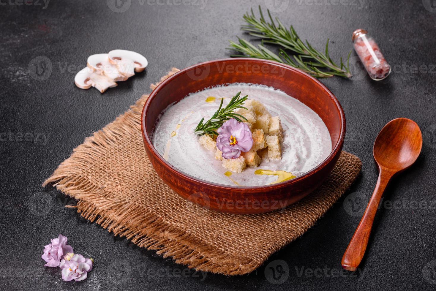 deliciosa sopa de hongos hermosa en un plato marrón con una cuchara de madera foto