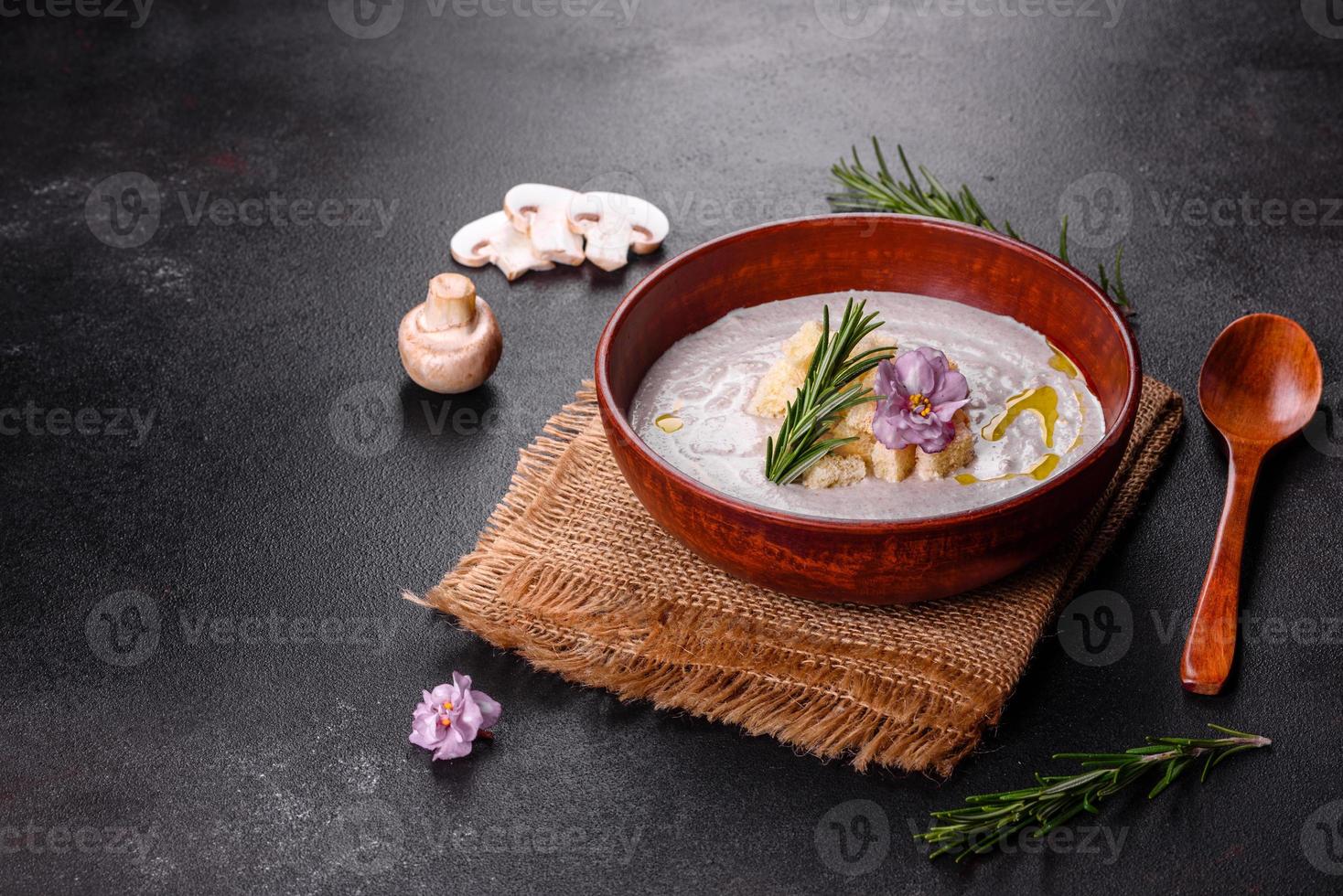 deliciosa sopa de hongos hermosa en un plato marrón con una cuchara de madera foto