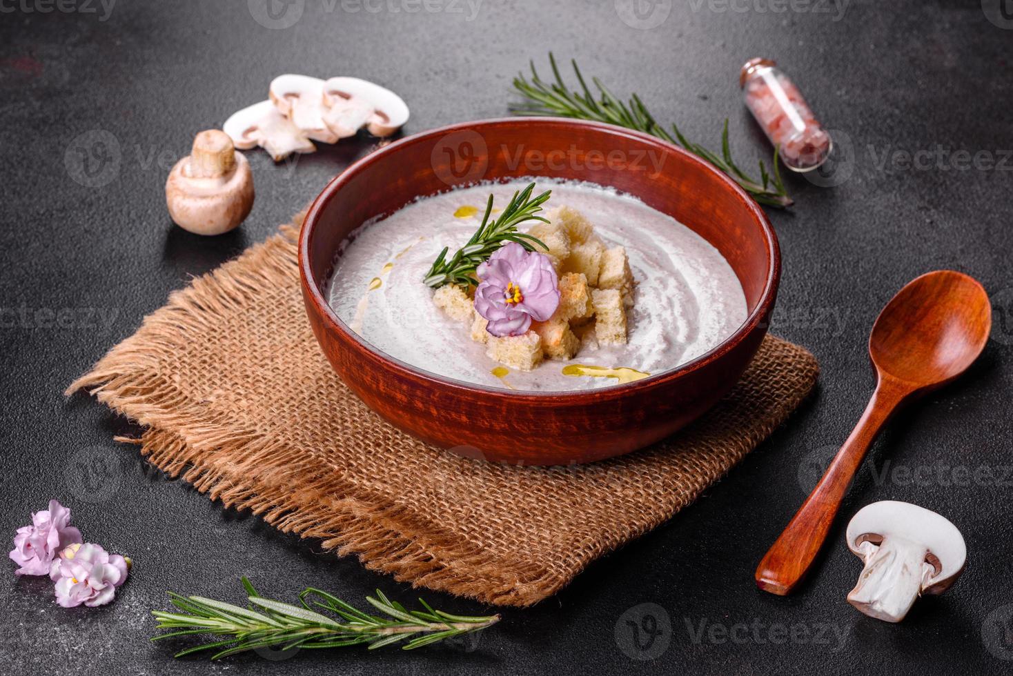 deliciosa sopa de hongos hermosa en un plato marrón con una cuchara de madera foto