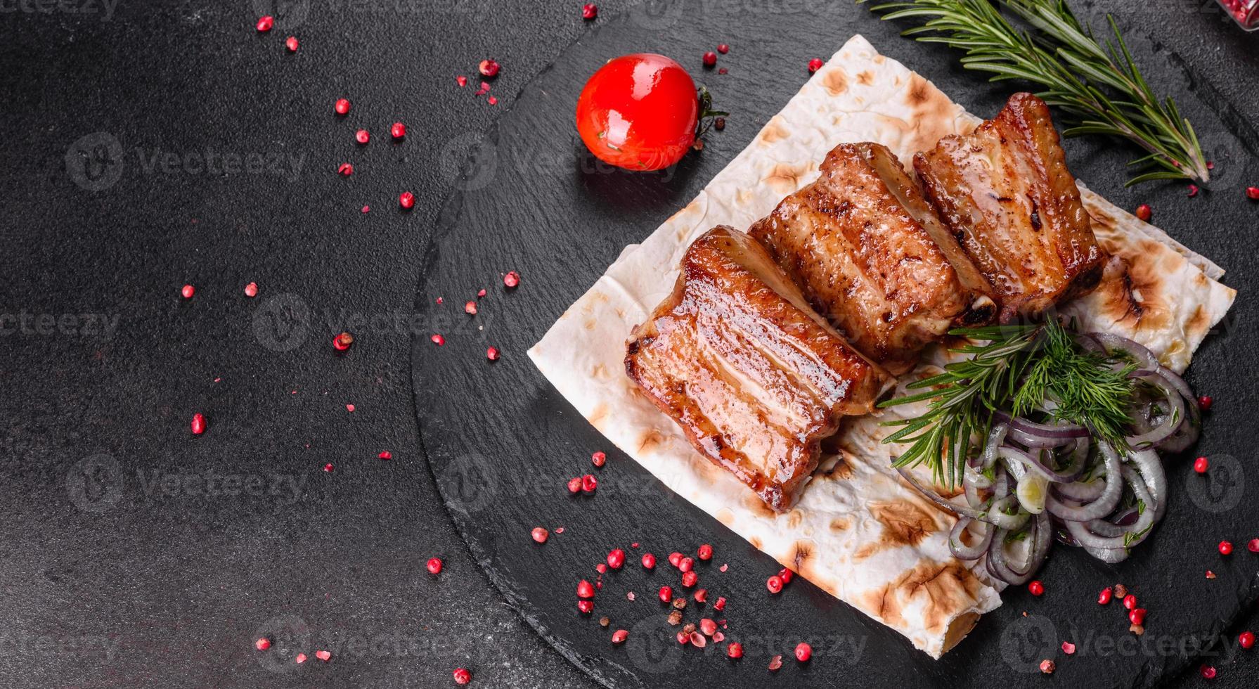 Costillas fritas con romero, cebolla, salsa sobre un fondo de hormigón foto