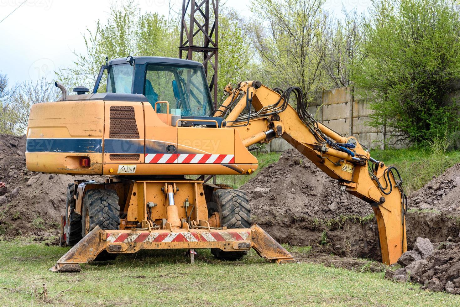 The modern excavator performs excavation work on the construction site photo