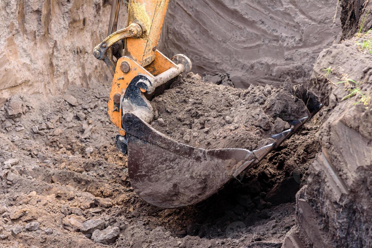 The modern excavator performs excavation work on the construction site photo