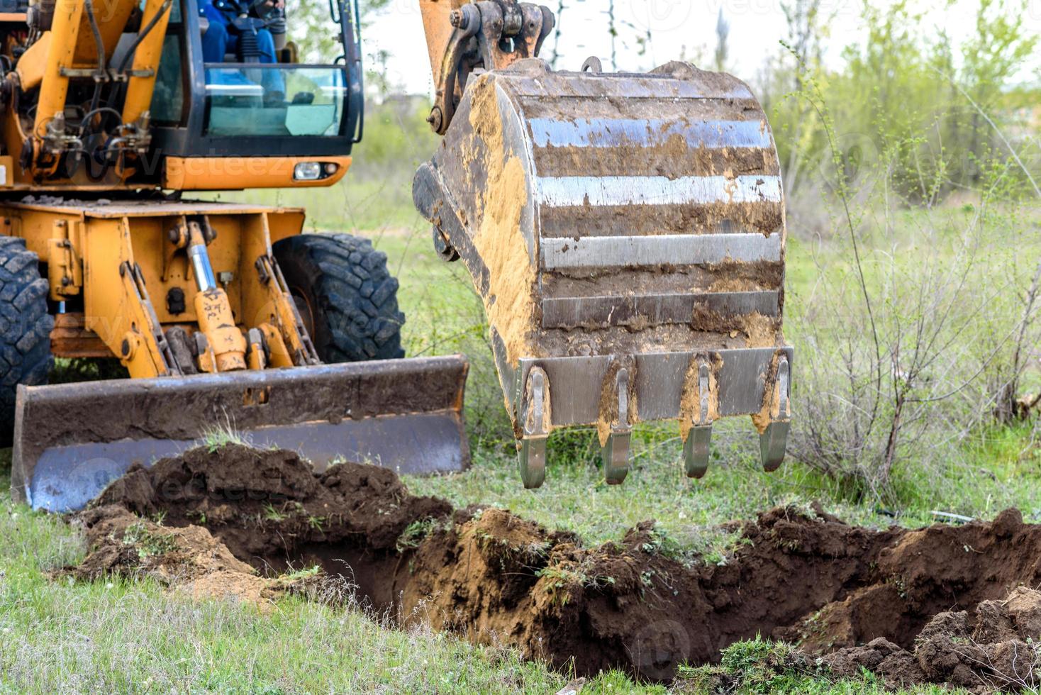 The modern excavator performs excavation work on the construction site photo