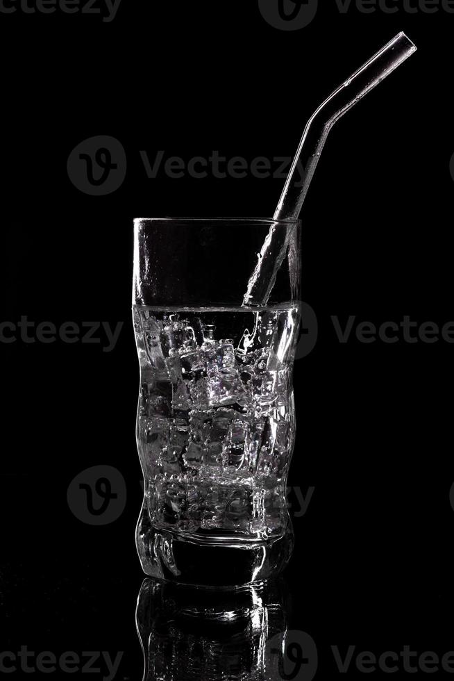 Glass of sparkling water soda drink with ice on black background photo