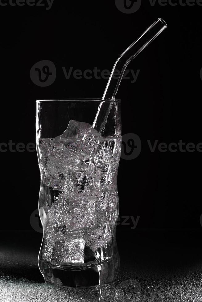 Glass of sparkling water soda drink with ice on black background photo