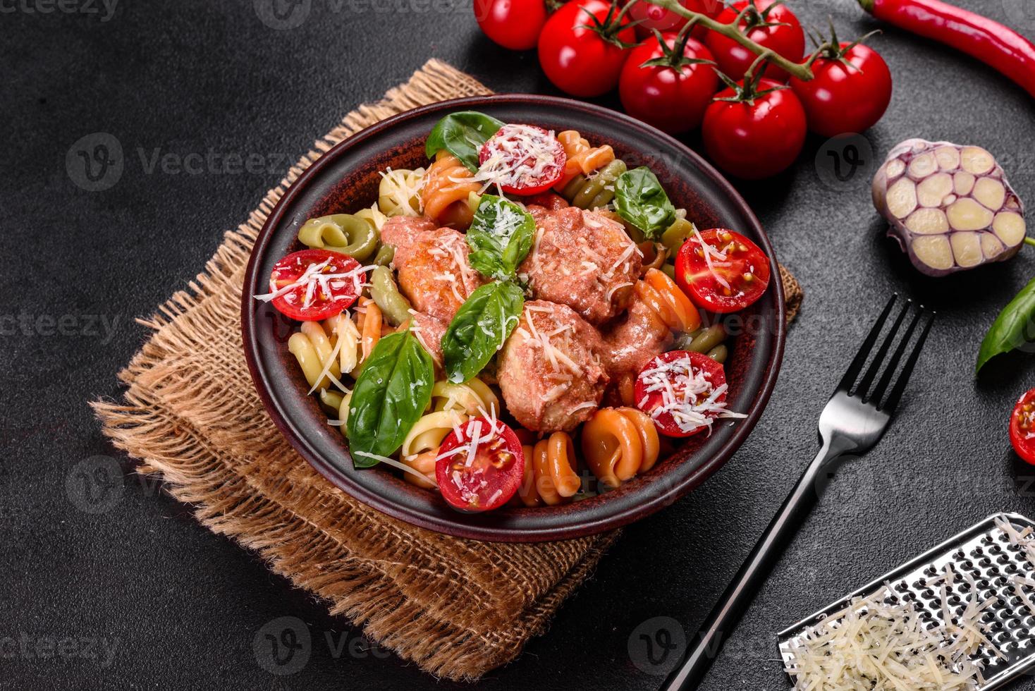 Delicious fresh pasta with meatballs, sauce, cherry tomatoes and basil photo