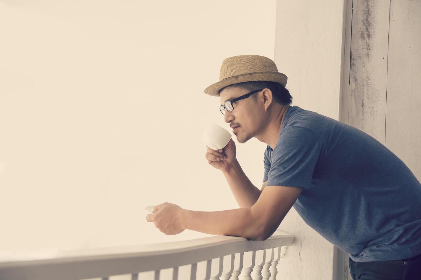 Handsome young man with cup of coffee enjoying life on outside balcony photo