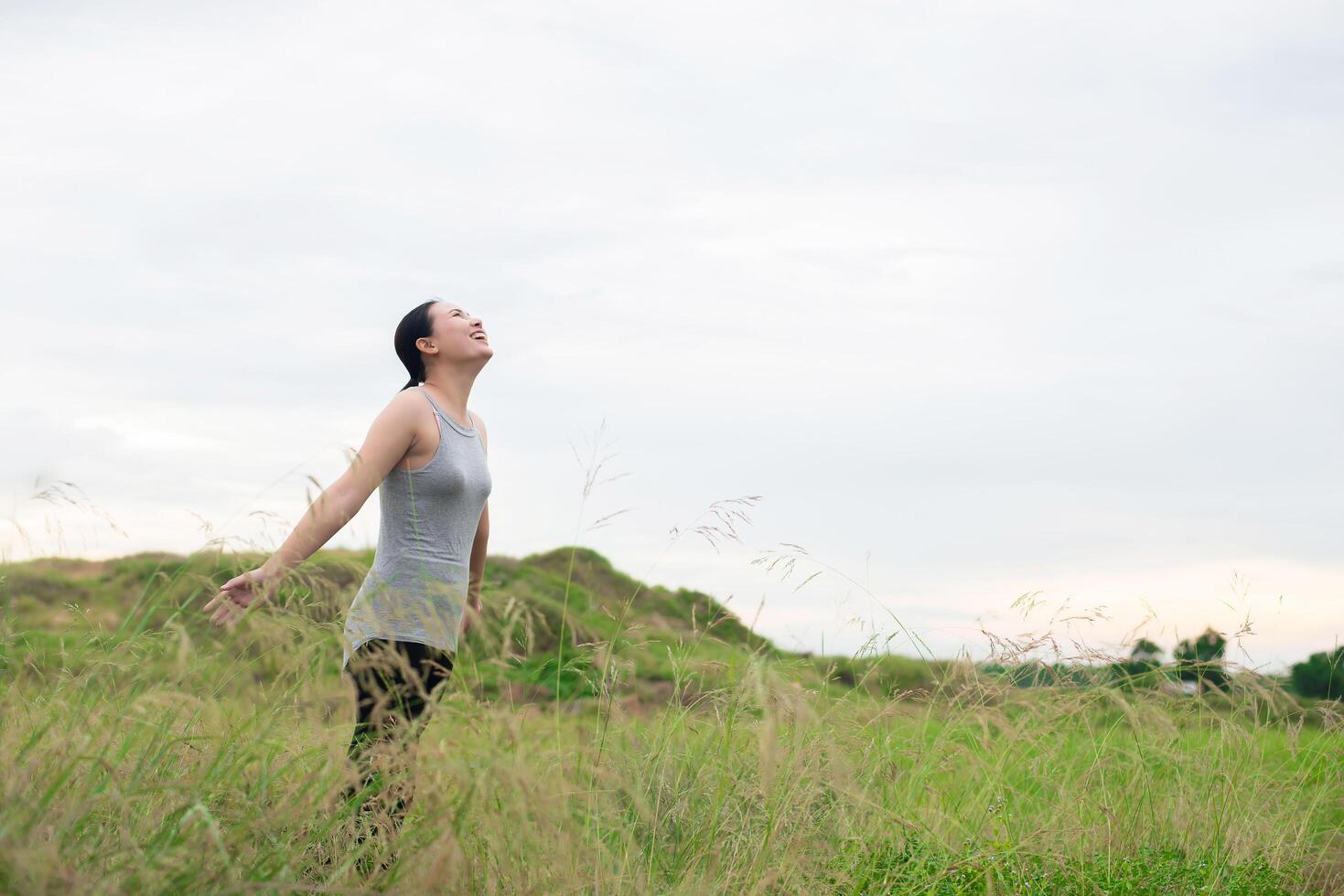 Young beautiful woman spreading hands with joy and inspiration at meadows photo