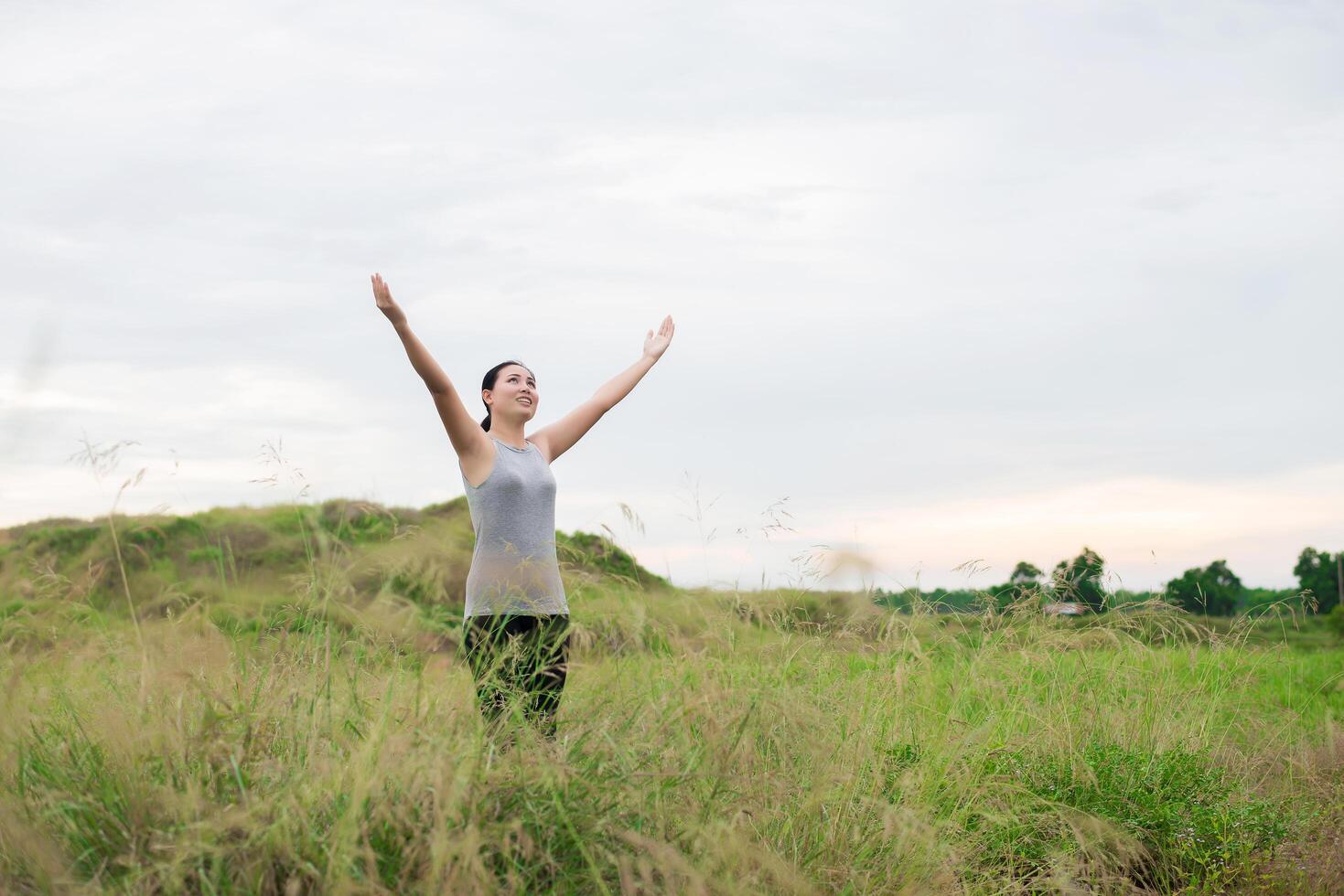 Young beautiful woman spreading hands with joy and inspiration at meadows photo