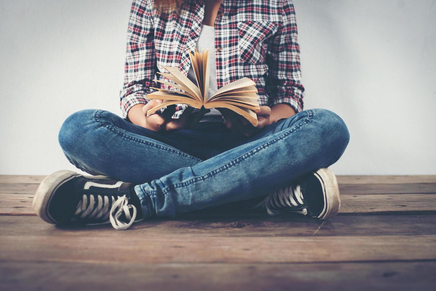Close-up of hipster woman hands holding open book sitting on wooden. photo