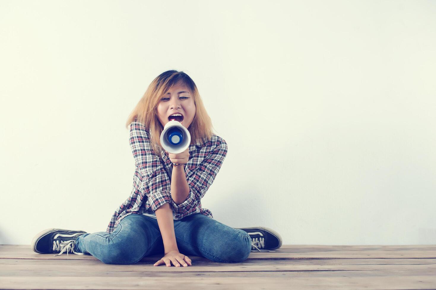 Young hipster woman shouting through megaphone. photo