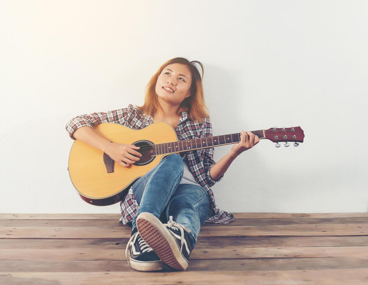 Retrato de estilo hipster mujer chillin con guitarra se ve tan feliz. foto