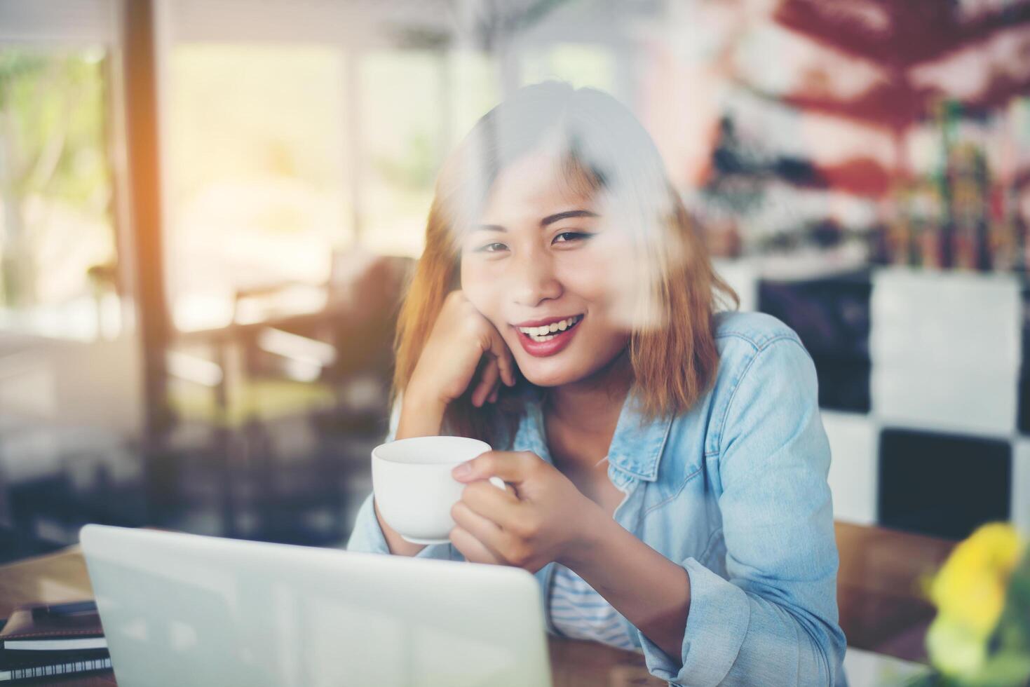 Young beautiful hipster woman work at cafe with window reflection. photo