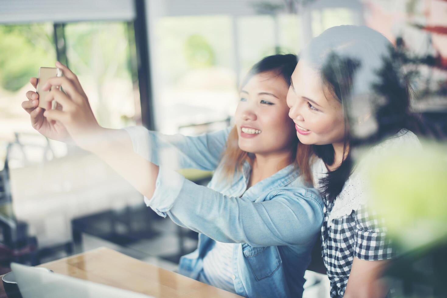 Two friends enjoying laying selfie together with window reflection photo