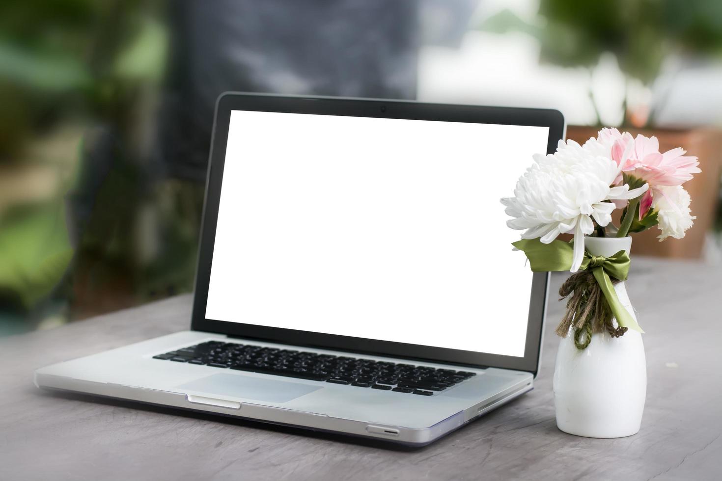 Laptop with blank screen on table and flower photo