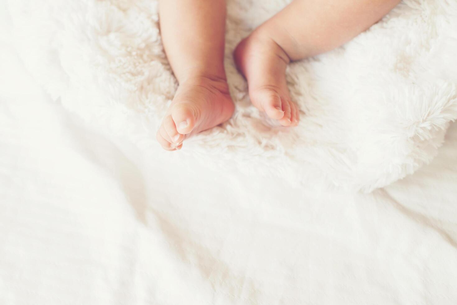 Newborn Baby legs on white bed. photo