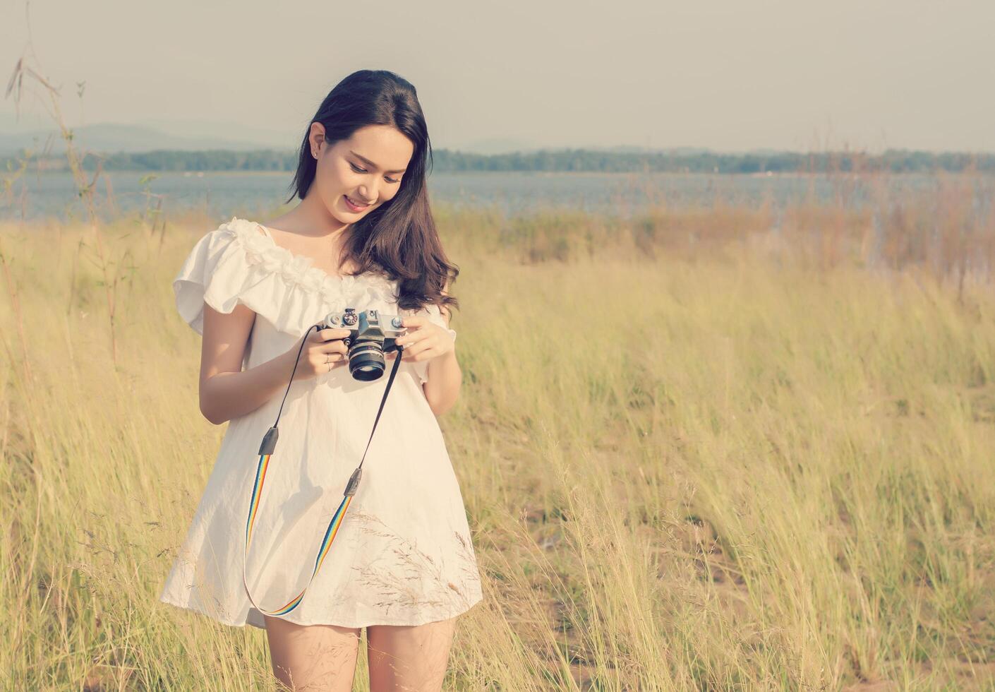 Woman photographer standing hand holding retro camera with sunrise photo