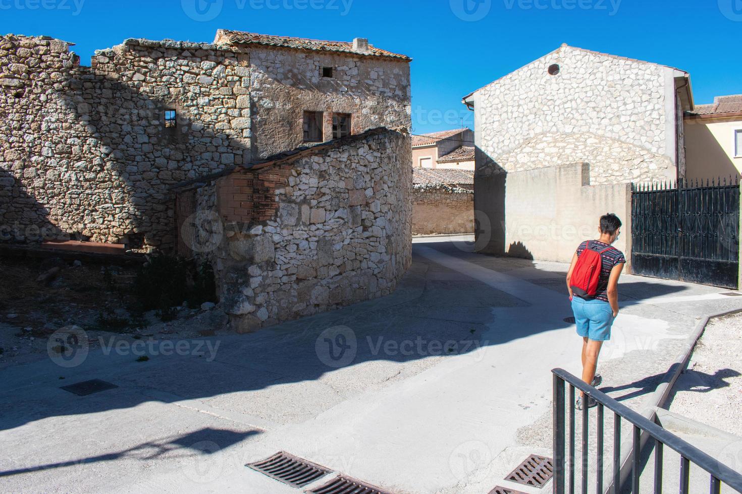 Mujer con mochila caminando por pueblo medieval foto