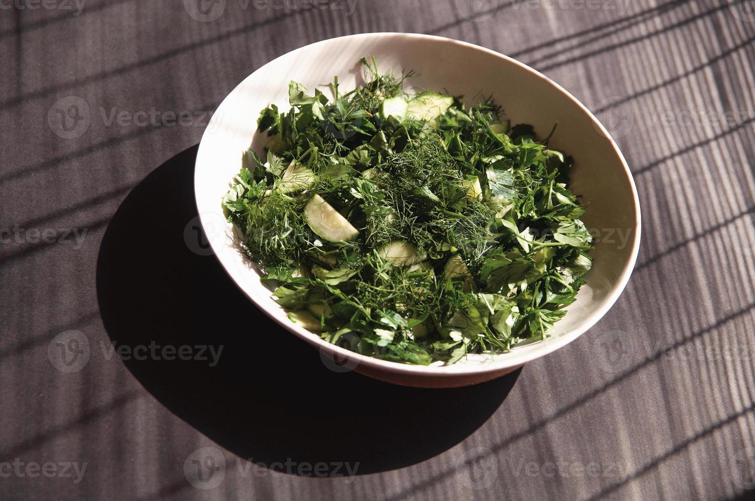 Ensalada con pepinos de eneldo y perejil en la placa un fondo gris foto