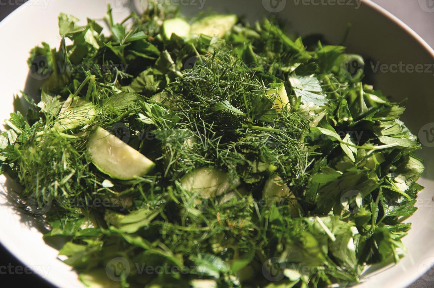 Ensalada con pepinos de eneldo y perejil en la placa un fondo gris foto