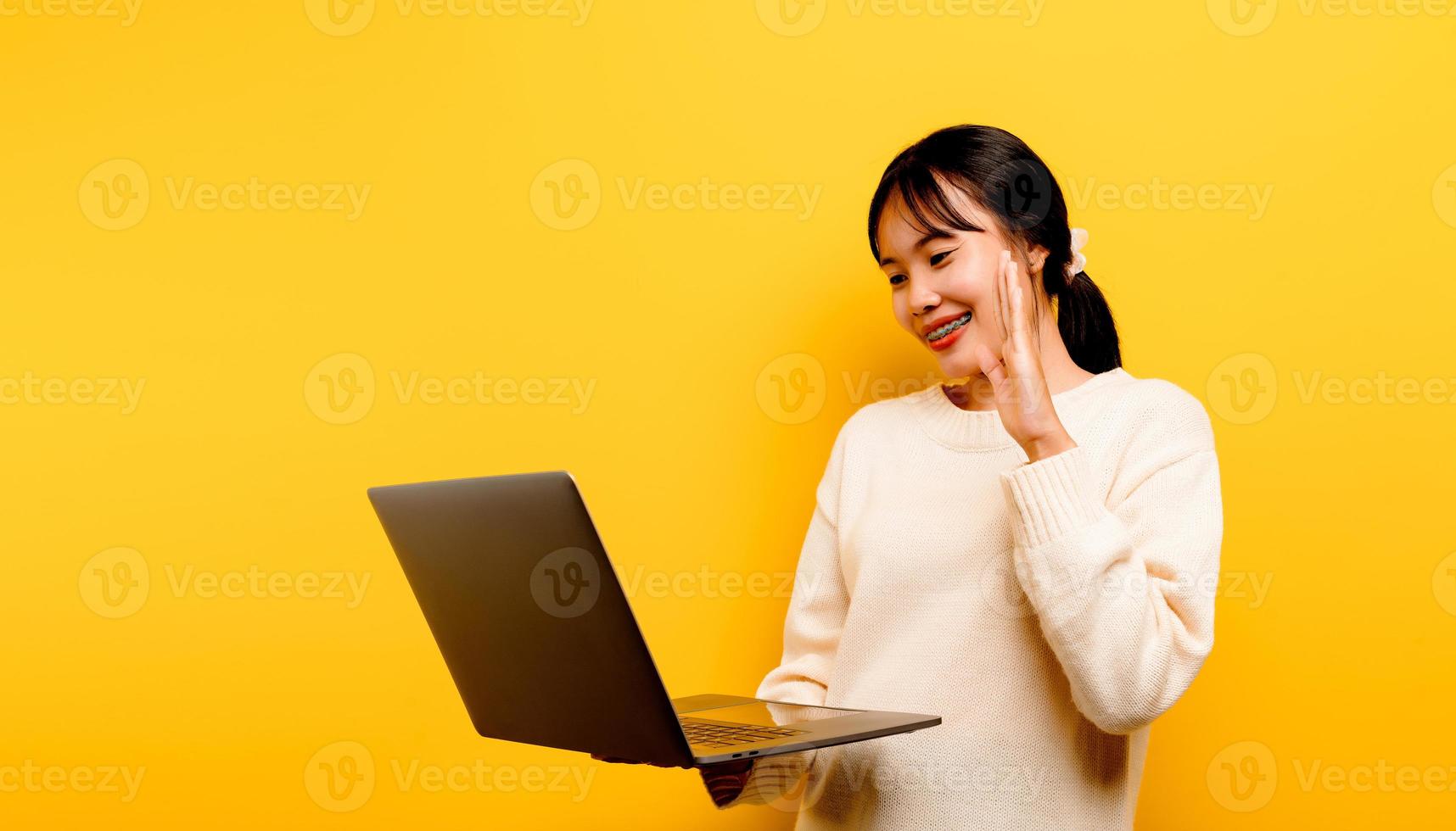 Concepto de comunicación en línea chica asiática usa portátil en casa amarillo foto