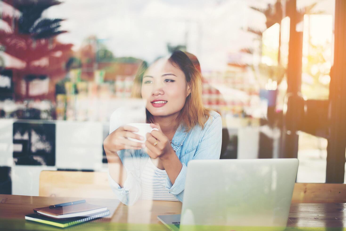 Mujer inconformista sosteniendo una taza de café y trabajando en el café foto