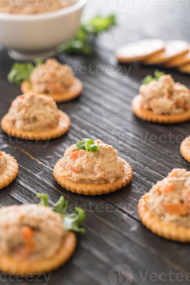 Tuna spread with cracker on wood board photo