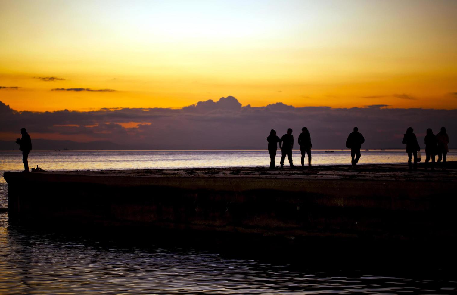 paisaje marino puesta de sol y silueta de personas foto