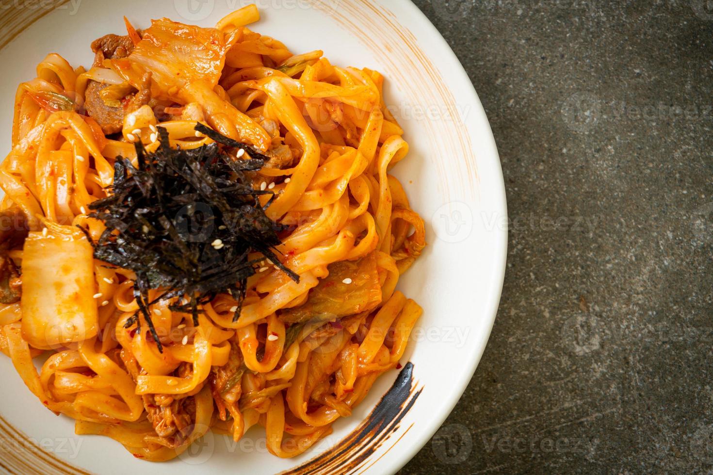 Stir-fried udon noodles with kimchi and pork - Korean food style photo