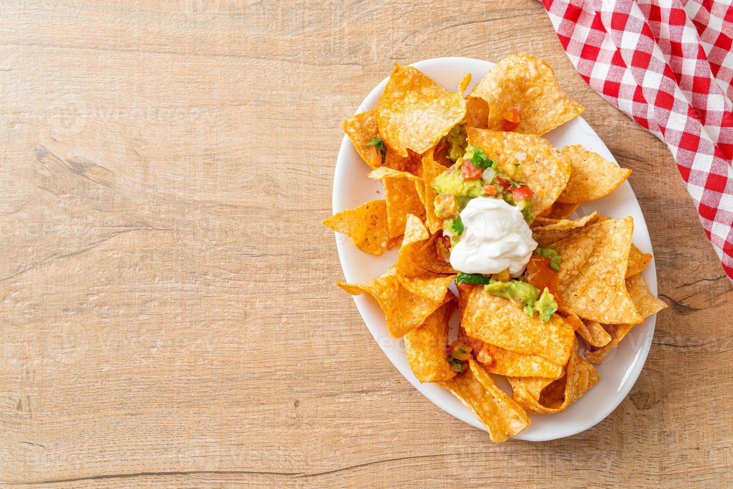 Mexican nachos tortilla chips with jalapeno, guacamole, tomatoes salsa and dip photo