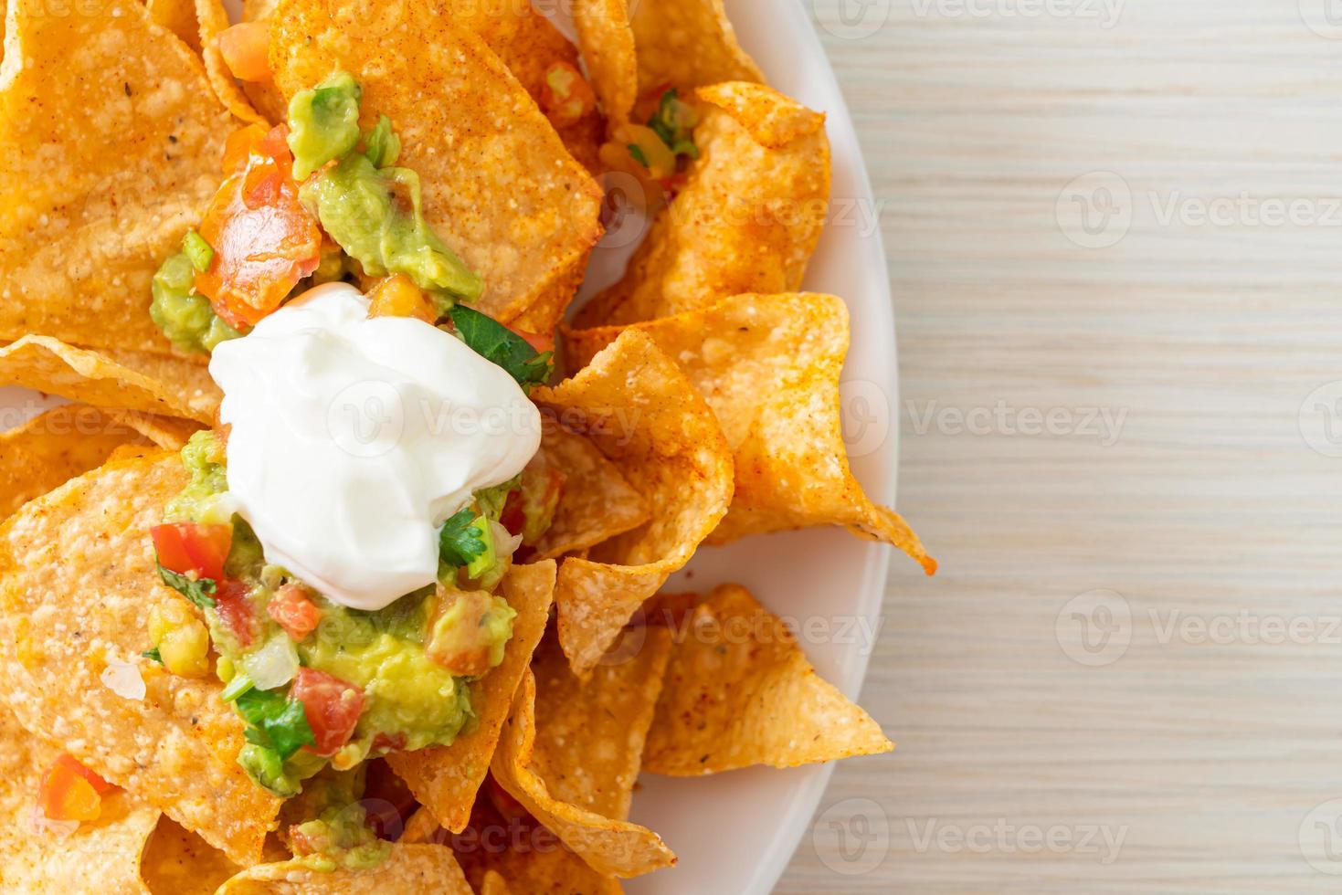 nachos mexicanos tortilla chips con jalapeño, guacamole, salsa de tomates y dip foto