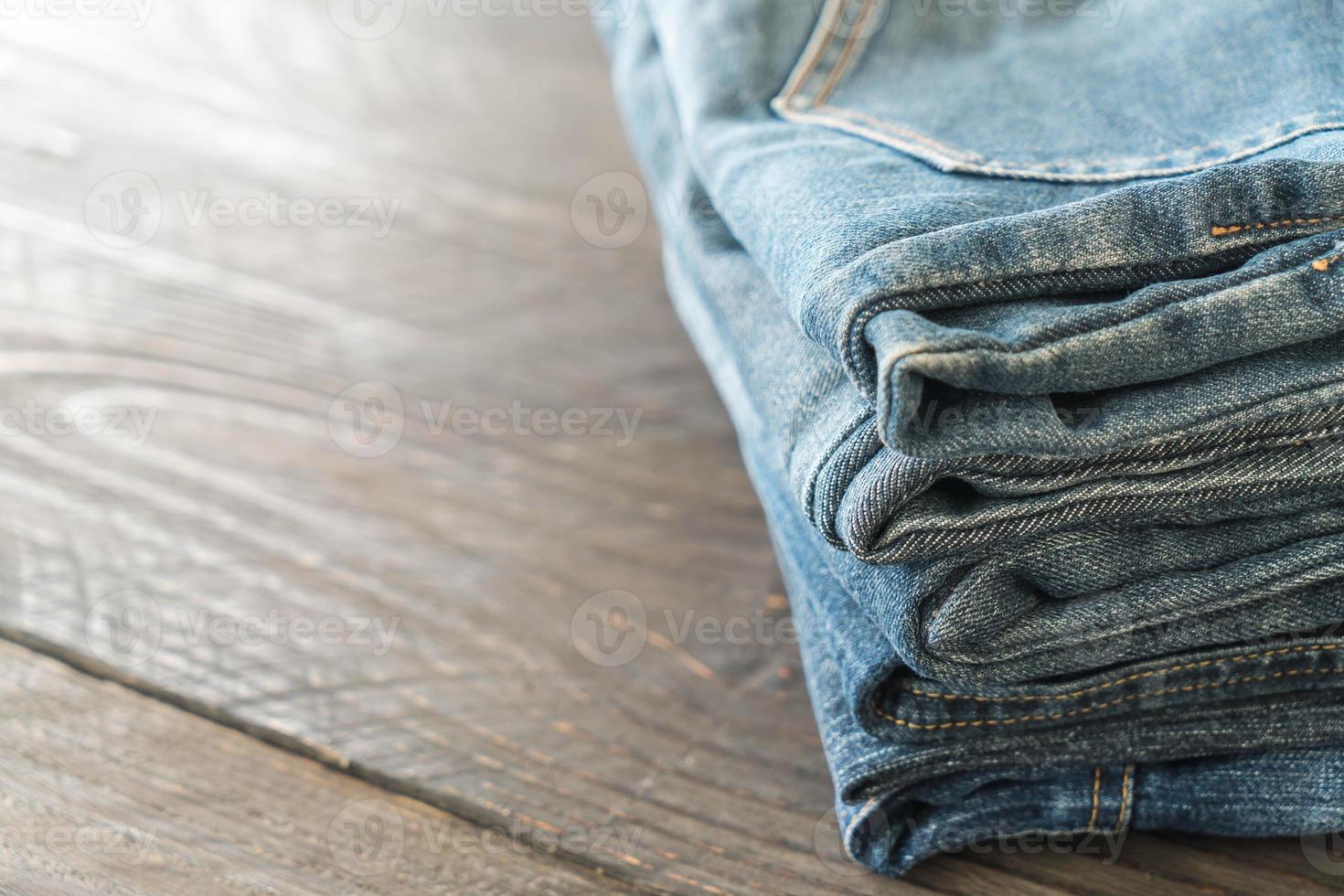 Stacks of jeans clothing on wood background photo