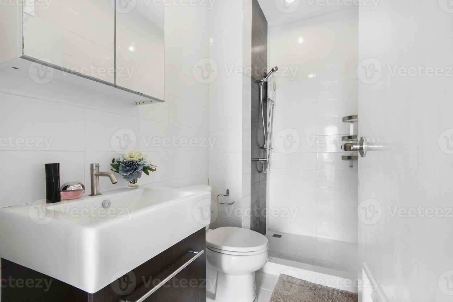 Baño blanco moderno y de madera con cabina de ducha de vidrio en el apartamento foto