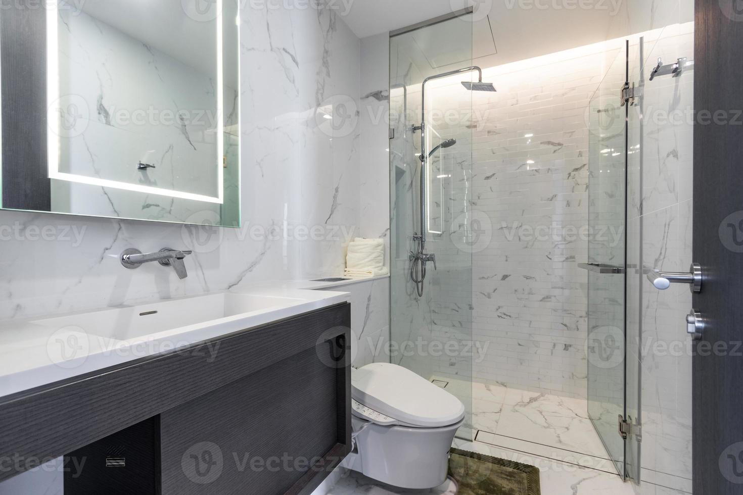 Baño blanco moderno y de madera con cabina de ducha de vidrio en el apartamento foto