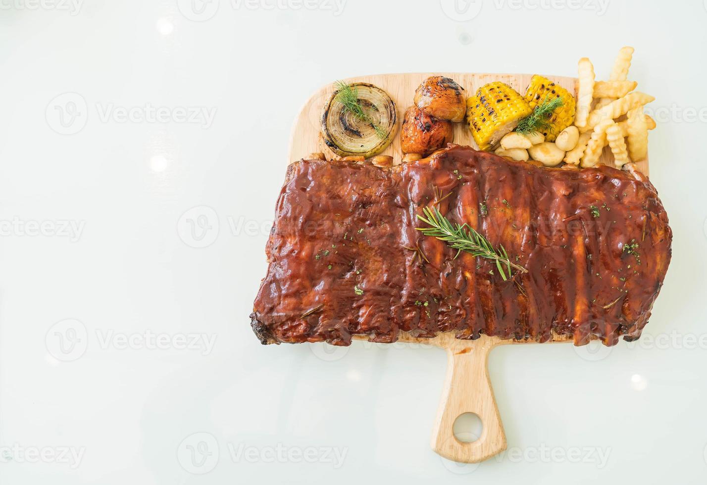 Costilla de cerdo a la plancha con salsa barbacoa y patatas fritas y verduras foto