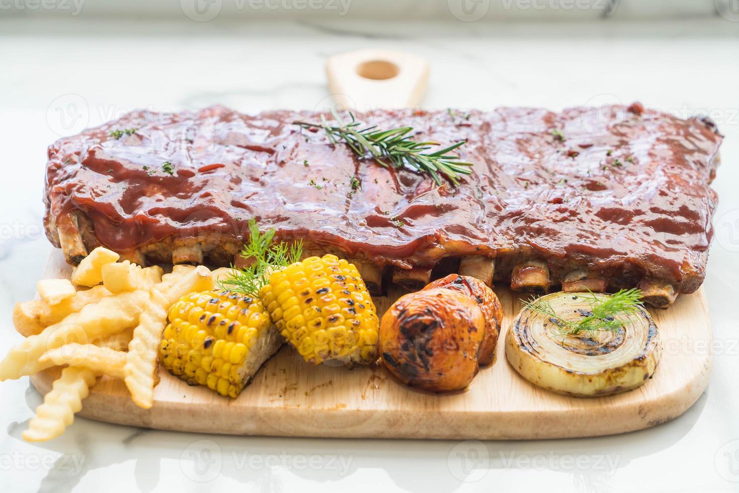 Costilla de cerdo a la plancha con salsa barbacoa y patatas fritas y verduras foto