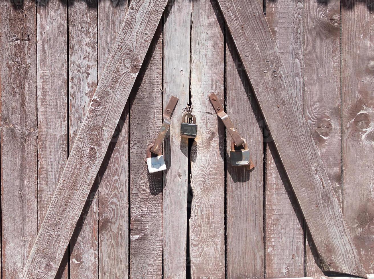 A wooden barn gate with closed padlocks photo