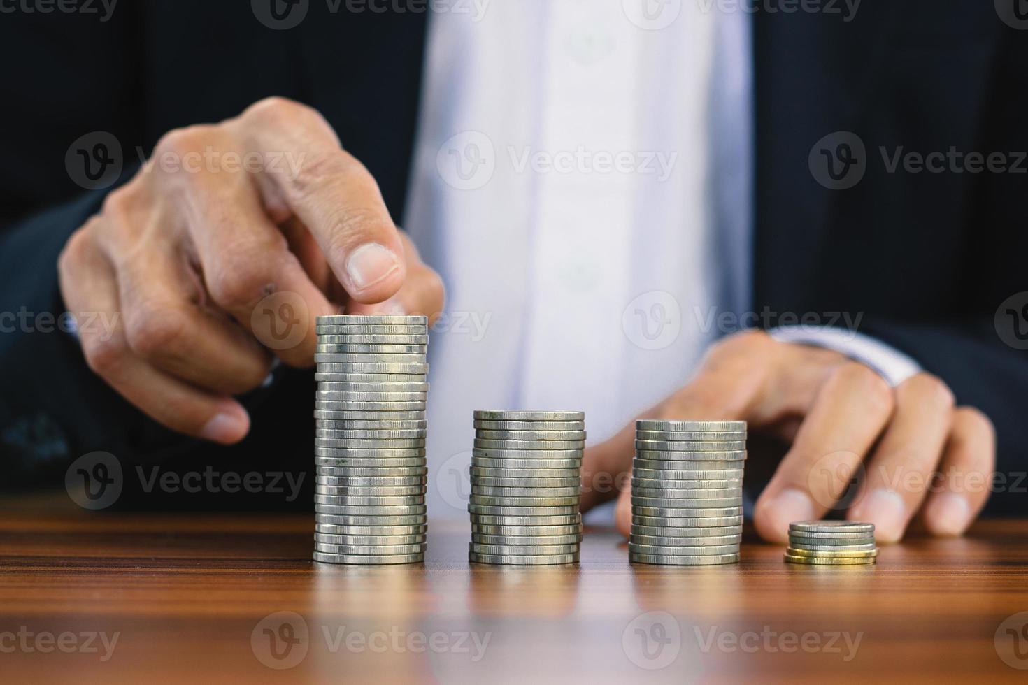 Mano contando la pila de monedas sobre la mesa de madera foto