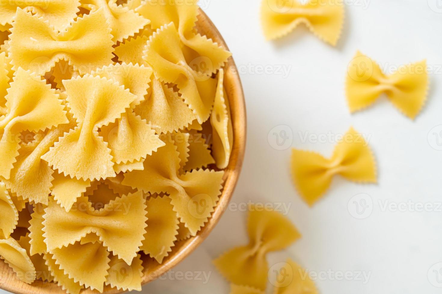 Dry uncooked farfalle pasta in bowl photo