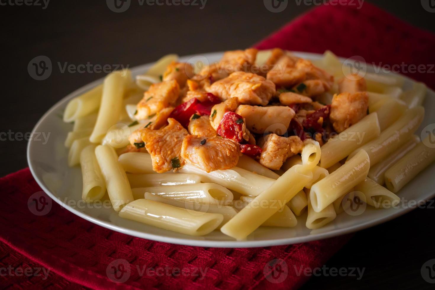 Penne pasta with chicken and vegetables in tomato sauce photo