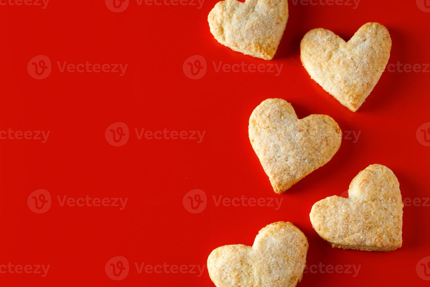 Galletas de azúcar en forma de corazón sobre fondo rojo. foto